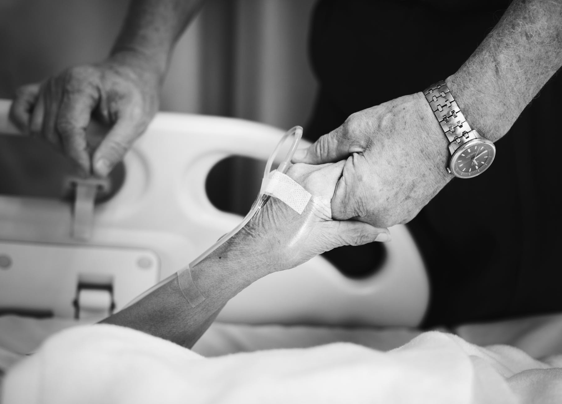 elderly couple holding hands hospital bed