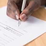 man's hand signing contract document