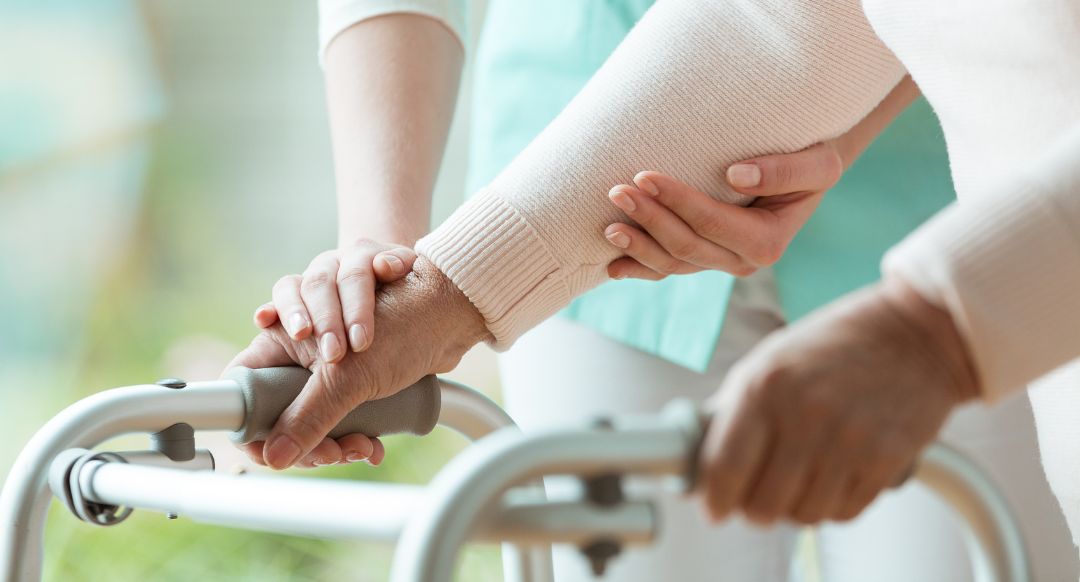 nursing home worker helps resident with walker