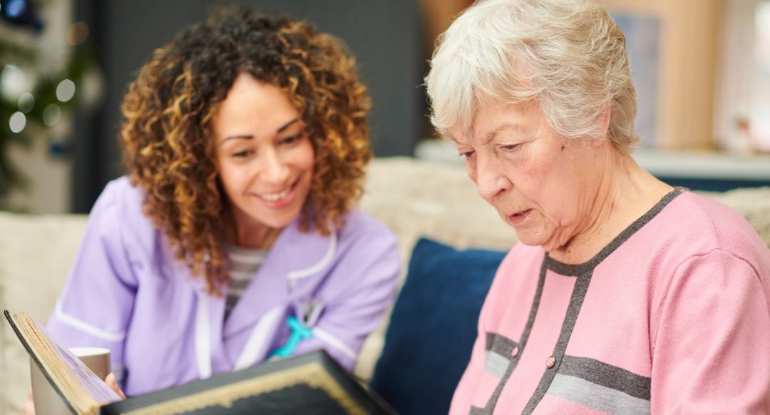 nursing home worker looking at photo album with elderly woman