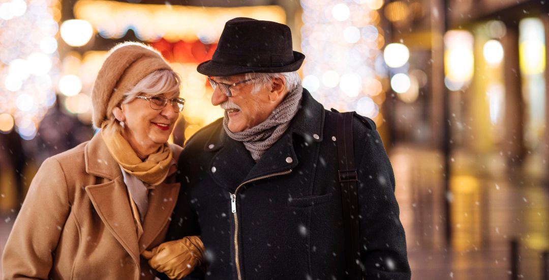 elderly couple walking arm in arm in the snow