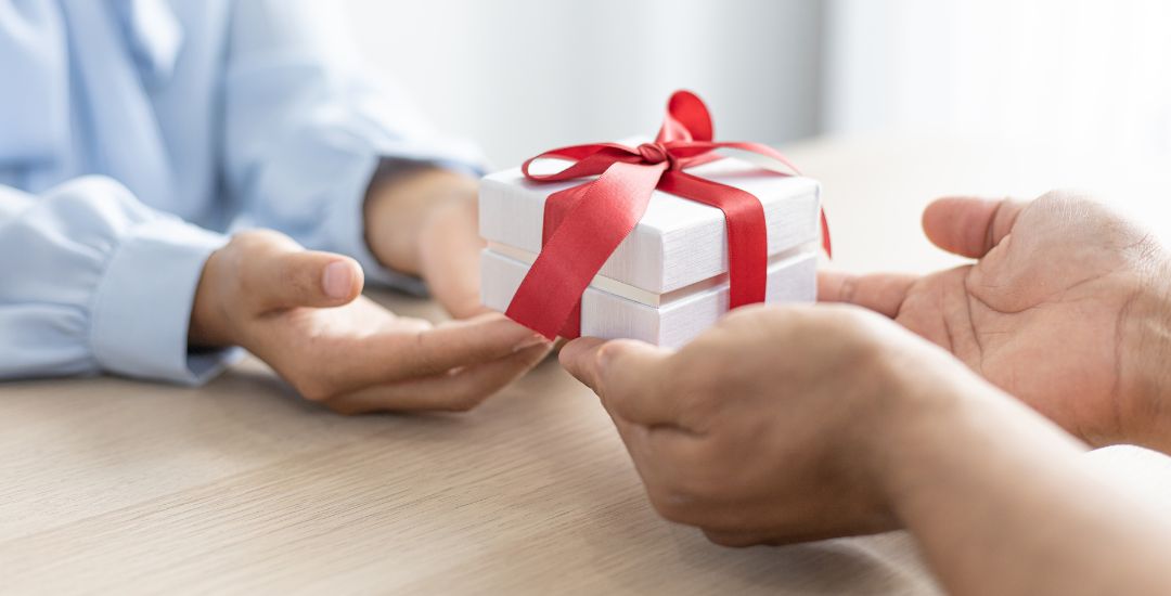 small gift with red bow passed between hands