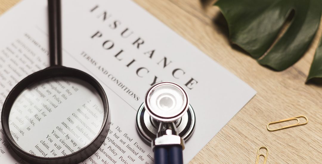 insurance policy document with stethoscope and magnifying glass