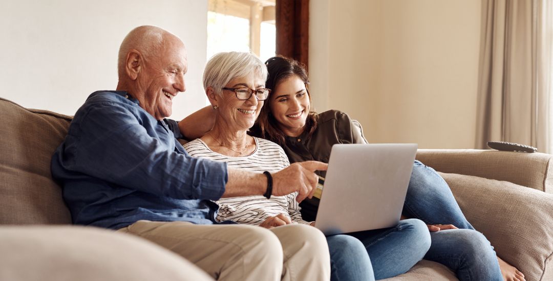 elderly couple with adult daughter looking at laptop